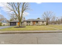 Charming single-story home with stone facade, updated black trim, and an inviting orange front door at 2951 E 62Nd St, Indianapolis, IN 46220