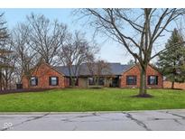 Charming red brick home featuring a well-manicured lawn and mature trees at 605 Sugarbush Dr, Zionsville, IN 46077