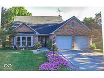 Charming brick home featuring a well-manicured lawn, mature trees, and an attached two-car garage at 7822 Ashton Ln, Fishers, IN 46038