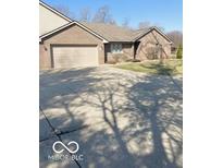Brick home featuring a two-car garage and a well-maintained lawn at 1103 Charleston Commons Dr, Anderson, IN 46012