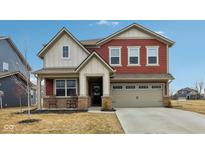 Inviting two-story home featuring red siding, a covered porch with rocking chairs, and an attached two-car garage at 1945 Clement St, Westfield, IN 46074