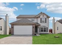 Charming two-story home with a well-manicured lawn and attached two-car garage at 3155 N White River Pkwy E Dr, Indianapolis, IN 46208