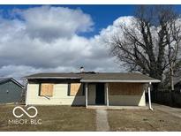 Damaged one-story home with boarded windows and siding damage needs renovation or rebuild at 3458 Carr Ave, Indianapolis, IN 46221