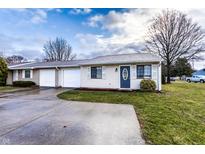 Charming one-story home features a front lawn, driveway, garage, and classic architecture under a cloudy sky at 8004 Minlo Dr, Indianapolis, IN 46227
