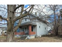 Classic two-story home featuring a welcoming front porch with brick columns and mature trees at 951 N Tuxedo St, Indianapolis, IN 46201