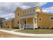 Charming two-story home with yellow siding, a covered porch, and well-manicured landscaping at 10483 St Anne Dr, Zionsville, IN 46077