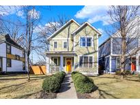 Charming two-story home featuring a bright yellow door and well-manicured landscaping at 1422 Carrollton Ave, Indianapolis, IN 46202