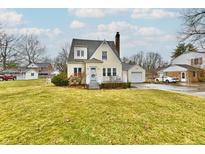Charming yellow two-story home with an attached garage and a large front yard at 19 Orchard Ln, Anderson, IN 46011
