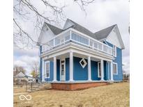 Charming two-story blue home with a covered porch, white pillars, and an upper-level deck at 300 E North Main St, Summitville, IN 46070