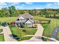 Stunning aerial view of the estate home featuring a pool, pond, large lawn and mature trees at 3537 Old Quarry Dr, Zionsville, IN 46077