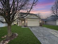 Charming home with a two-car garage, green lawn and beautiful landscaping at sunset at 5816 Dollar Forge Dr, Indianapolis, IN 46221