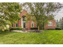 Charming two-story brick home with arched entryway, manicured lawn, and mature trees at 14297 Matt St, Carmel, IN 46033