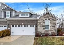 Charming townhome showcasing a two-car garage, stone facade, and well-maintained landscaping at 14474 Treasure Creek Ln, Fishers, IN 46038