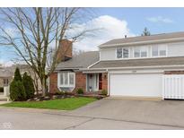 Charming townhome featuring a red brick facade, bay window, attached garage, and well-maintained landscaping at 1457 Dominion Dr, Zionsville, IN 46077
