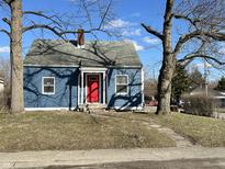 Charming blue home with a red door and mature trees at 2001 Glenridge Dr, Indianapolis, IN 46218