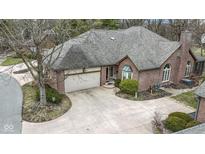 Brick home features a two-car garage, mature trees, and a cozy entrance with a bench and landscaping at 2042 Oldfields Cir N Dr, Indianapolis, IN 46228