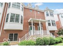 Brick townhome with white trim, green doors, a stone foundation, and neatly trimmed shrubs at 839 N Park Trail Dr, Carmel, IN 46032