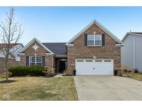 Charming brick home featuring an attached two-car garage, well-kept lawn and landscaping at 8708 N Deer Crossing Blvd, McCordsville, IN 46055