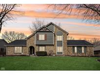Charming two-story stone and wood home with a well-maintained lawn and colorful sunset sky at 9132 Log Run N Dr, Indianapolis, IN 46234