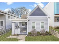Charming home with a gabled roof, covered porch, tidy landscaping, and freshly painted gray siding at 1210 S State Ave, Indianapolis, IN 46203