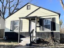 Charming home with light yellow siding and black trim, featuring a covered front porch at 1422 E 49Th St, Indianapolis, IN 46205