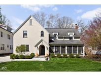 Charming two-story home featuring a well-manicured lawn, stucco exterior, and cozy screened porch at 4310 Central Ave, Indianapolis, IN 46205