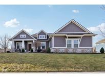 Charming gray home featuring stone accents, manicured lawn and inviting covered porch, perfect for suburban living at 5955 Stroup Dr, Noblesville, IN 46062