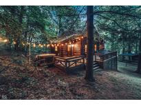 Charming log cabin nestled in a wooded setting with string lights and a cozy, inviting atmosphere at 6688 Bellsville Pike, Columbus, IN 47201