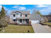 Charming two-story home boasts a brick and gray facade, well-manicured lawn, and an attached two-car garage at 933 Queensbury Dr, Noblesville, IN 46062