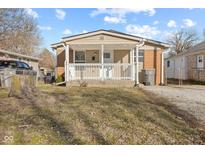 Charming home featuring a cozy front porch with white railings and a combination of brick and siding exterior at 1131 Madeira St, Indianapolis, IN 46203
