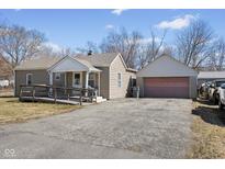 View of a single-story home with a ramp to the front door and a detached garage with a wide driveway at 1205 S Dequincy St, Indianapolis, IN 46203