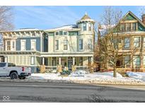 Charming Victorian home featuring a unique turret, covered porch, and snowy front yard, showcasing classic architectural details at 1471 N Delaware St, Indianapolis, IN 46202