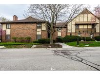 Brick townhouse features a walkway and a neatly landscaped front yard with mature trees and flowering shrubs at 3840 Knollton Rd # A, Indianapolis, IN 46228