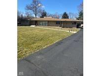 Ranch-style home with a lush lawn, stone facade, and long driveway on a sunny day at 6630 Spring Mill Rd, Indianapolis, IN 46260