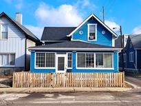 Charming two-story blue home with a well-manicured lawn, a black roof, and a partially fenced yard at 726 E Mccarty St, Indianapolis, IN 46203