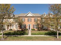 Charming brick townhome with well-maintained landscaping and inviting entrance with Autumn colored trees at 13504 E 131St St, Fishers, IN 46037
