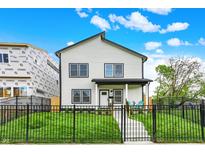 Charming two-story home with black trim, a well-manicured lawn, and a black metal fence at 35 N Keystone Ave, Indianapolis, IN 46201