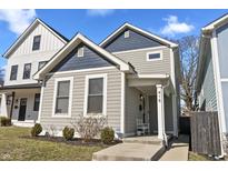 Charming gray two-story home featuring blue trim, landscaped yard, and inviting front porch at 418 Sanders St, Indianapolis, IN 46225