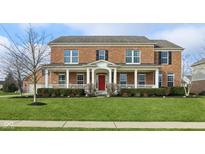 Charming two-story brick home featuring a welcoming front porch with classic white columns and a vibrant red front door at 4604 S Cobblestone Dr, Zionsville, IN 46077