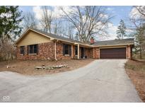 Beautiful brick home with a two-car garage, manicured lawn, and a long driveway leading to the house at 5125 E 79Th St, Indianapolis, IN 46250