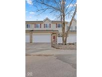 Traditional townhome featuring a two-car garage, light beige siding, and a manicured front yard at 5839 Beacon Cove Way, Indianapolis, IN 46237