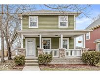 Charming two-story home with a welcoming front porch featuring brick columns and a well-maintained yard at 827 N Tacoma Ave, Indianapolis, IN 46201