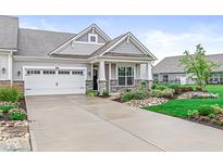 Charming home exterior with a two-car garage, stone accents and manicured landscaping at 9442 Orchard Cove Dr, Indianapolis, IN 46239
