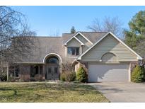 Charming two-story home featuring a brick facade, arched entryway, and attached two-car garage at 1110 Butternut Dr, Columbus, IN 47201