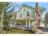 Charming two-story home with a gambrel roof, inviting front porch with swing, and brick chimney at 140 E 44Th St, Indianapolis, IN 46205