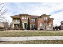 Traditional two-story brick home with a covered porch and manicured lawn at 14375 Alderbrook Trl, Carmel, IN 46033