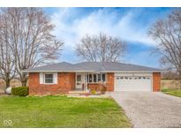 Charming one-story brick home featuring an attached two-car garage and well-manicured lawn at 15620 E State Road 46, Columbus, IN 47203