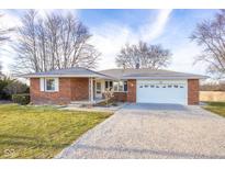 Charming brick ranch-style home featuring a well-maintained yard and a spacious gravel driveway at 15620 E State Road 46, Columbus, IN 47203