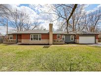 Charming single-story home featuring brick and stone exterior, manicured lawn, and attached garage at 405 W 73Rd St, Indianapolis, IN 46260