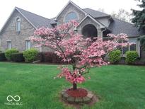 Charming two-story home with lush green lawn and a beautiful dogwood tree in full bloom at 4927 Auburn Ford, Greenwood, IN 46142